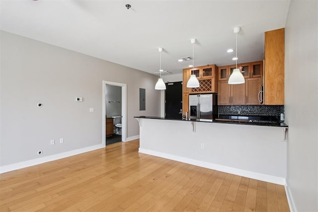 444 N Central Ave Unit 204, Oklahoma City, OK 73104 - kitchen with appliances with stainless steel finishes, brown cabinetry, dark countertops, a peninsula, and hanging light fixtures