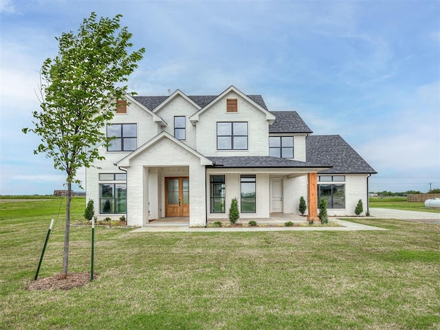 7431 NE Hawk Dr, Piedmont, OK 73078 - modern farmhouse featuring roof with shingles, a front yard, and covered porch
