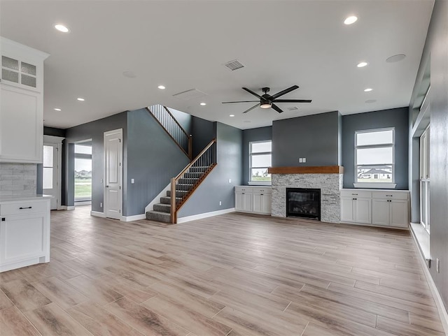 7431 NE Hawk Dr, Piedmont, OK 73078 - unfurnished living room featuring a fireplace, a ceiling fan, light wood finished floors, stairway, and recessed lighting