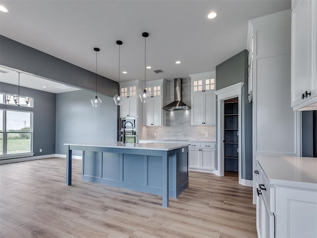 7431 NE Hawk Dr, Piedmont, OK 73078 - kitchen featuring wall chimney range hood, decorative backsplash, white cabinets, light countertops, and recessed lighting