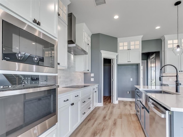 7431 NE Hawk Dr, Piedmont, OK 73078 - kitchen featuring stainless steel appliances, wall chimney range hood, light countertops, glass insert cabinets, and tasteful backsplash