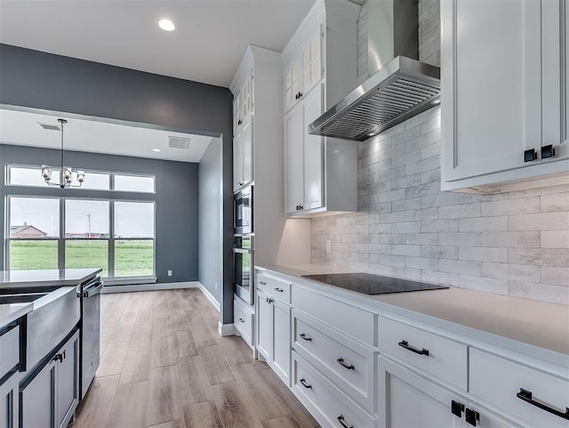 7431 NE Hawk Dr, Piedmont, OK 73078 - kitchen featuring wall chimney exhaust hood, stainless steel appliances, light countertops, white cabinets, and hanging light fixtures