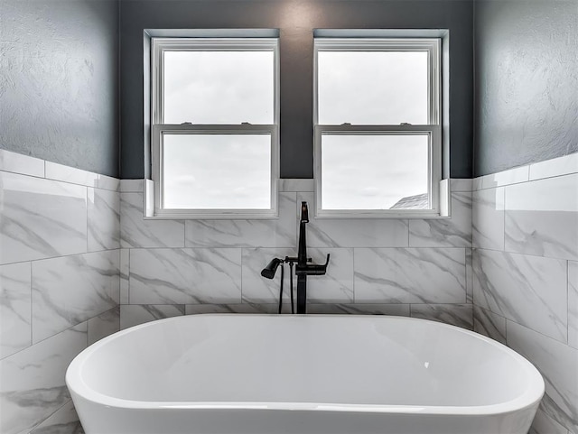 7431 NE Hawk Dr, Piedmont, OK 73078 - full bathroom with tile walls, a freestanding bath, and plenty of natural light