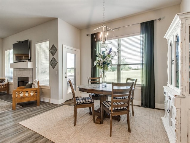 2315 Dixie Dr, Blanchard, OK 73010 - dining space with light wood-style flooring, a chandelier, a stone fireplace, and healthy amount of natural light