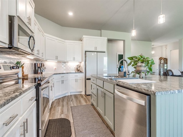 2315 Dixie Dr, Blanchard, OK 73010 - kitchen featuring stainless steel appliances, light wood-type flooring, a kitchen island with sink, tasteful backsplash, and white cabinetry