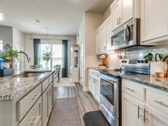 2315 Dixie Dr, Blanchard, OK 73010 - kitchen featuring stainless steel appliances, light wood finished floors, backsplash, and stone countertops