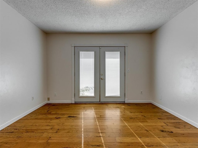 1800 Michael Dr, Edmond, OK 73013 - empty room with hardwood / wood-style floors, a textured ceiling, and french doors