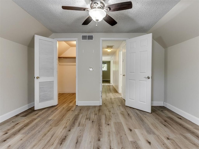 1800 Michael Dr, Edmond, OK 73013 - unfurnished bedroom with vaulted ceiling, a walk in closet, light wood finished floors, a textured ceiling, and a ceiling fan