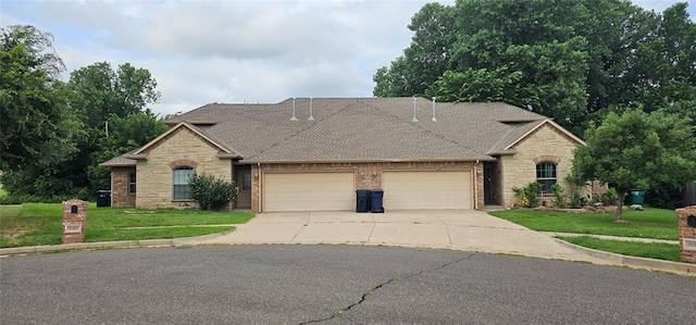12201 Buckingham Ln, Yukon, OK 73099 - view of front facade featuring an attached garage, stone siding, and driveway