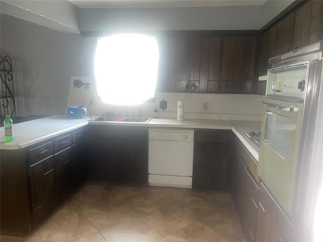 kitchen with white dishwasher, oven, light countertops, and dark brown cabinets