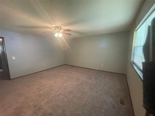 empty room featuring a ceiling fan, carpet floors, and a textured ceiling