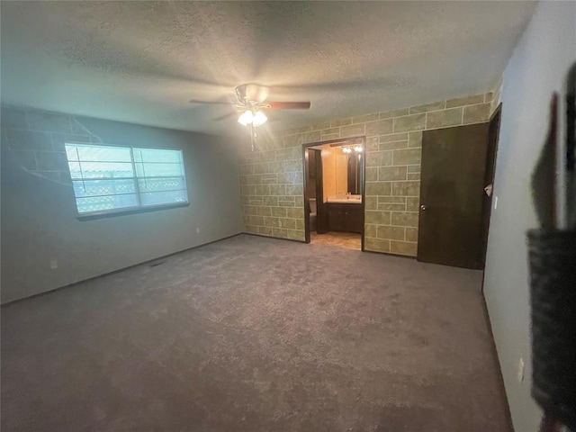unfurnished bedroom featuring a textured ceiling, carpet flooring, a ceiling fan, and ensuite bath