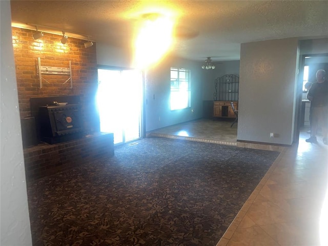 unfurnished living room with a textured ceiling, ceiling fan, and rail lighting