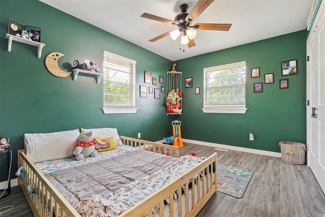 901 E Covell Rd, Edmond, OK 73034 - bedroom with multiple windows, wood finished floors, and a ceiling fan
