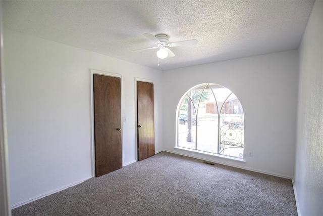 2328 NW 113th St, Oklahoma City, OK 73120 - unfurnished bedroom with carpet flooring, multiple closets, a textured ceiling, and a ceiling fan