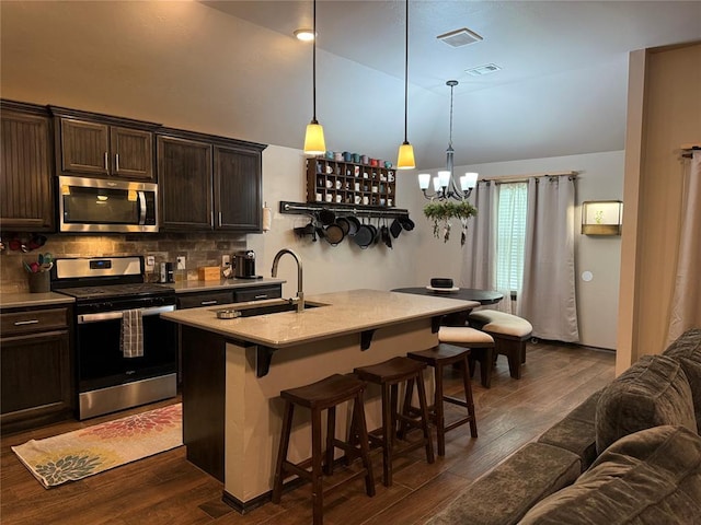 18641 Como Dr, Edmond, OK 73012 - kitchen with stainless steel appliances, a kitchen bar, dark brown cabinetry, dark wood-style flooring, and high vaulted ceiling