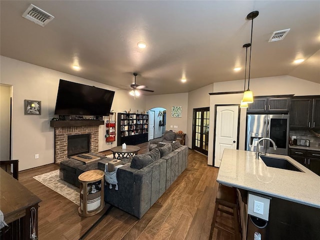 18641 Como Dr, Edmond, OK 73012 - living area with a ceiling fan, dark wood finished floors, a fireplace, arched walkways, and vaulted ceiling