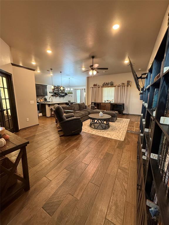 18641 Como Dr, Edmond, OK 73012 - living room with dark wood-style floors, a ceiling fan, and a chandelier