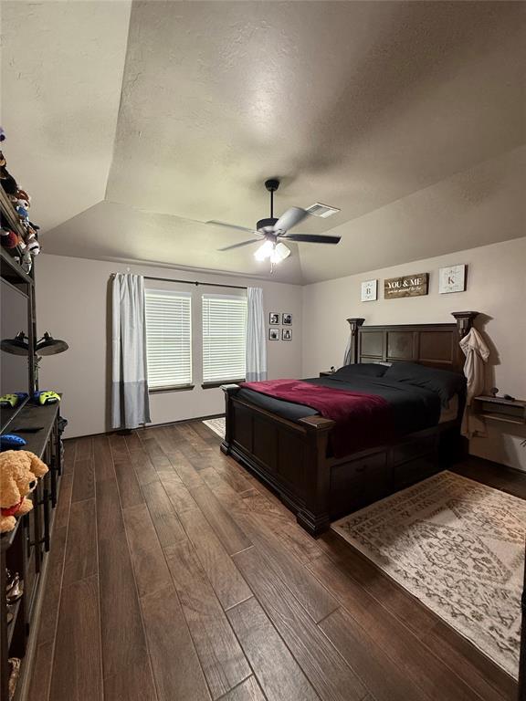 18641 Como Dr, Edmond, OK 73012 - bedroom featuring dark wood-style floors, vaulted ceiling, a ceiling fan, and a textured ceiling