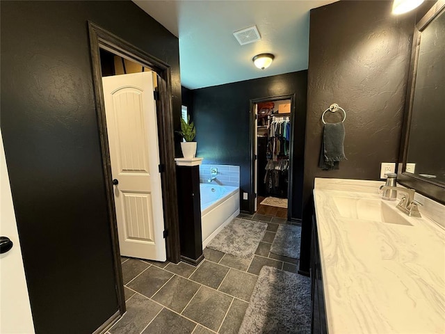 18641 Como Dr, Edmond, OK 73012 - bathroom with a garden tub, vanity, a walk in closet, and a textured wall