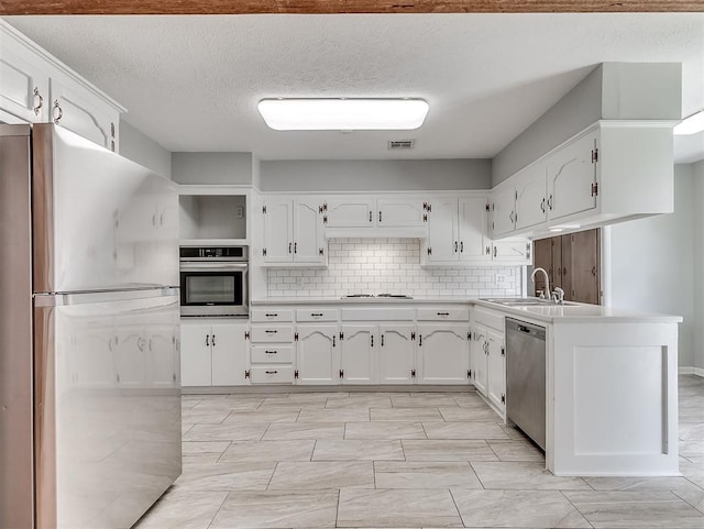 4325 NW 44th St, Oklahoma City, OK 73112 - kitchen with stainless steel appliances, white cabinetry, light countertops, decorative backsplash, and a textured ceiling