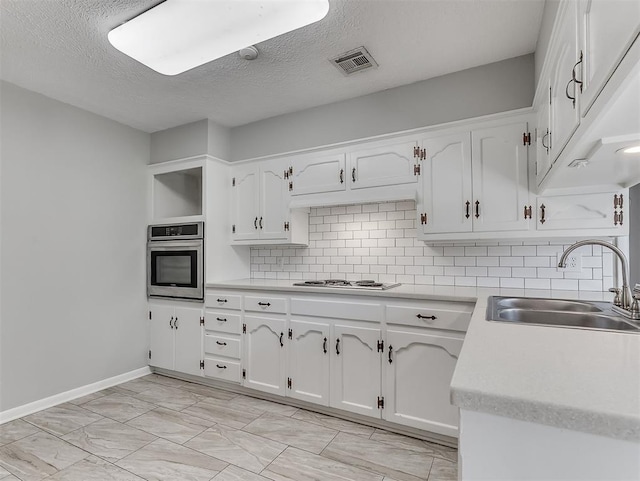 4325 NW 44th St, Oklahoma City, OK 73112 - kitchen with oven, tasteful backsplash, white cabinets, and a textured ceiling