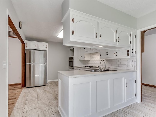 4325 NW 44th St, Oklahoma City, OK 73112 - kitchen featuring stainless steel appliances, a peninsula, light countertops, white cabinetry, and backsplash