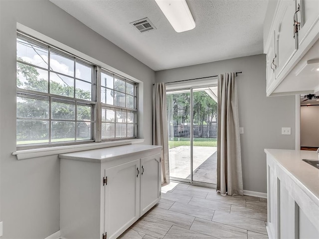 4325 NW 44th St, Oklahoma City, OK 73112 - kitchen featuring white cabinetry, light countertops, light marble finish floors, and a textured ceiling