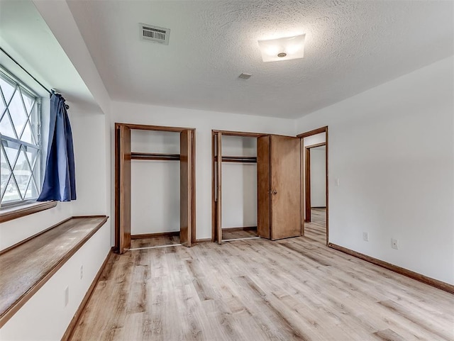 4325 NW 44th St, Oklahoma City, OK 73112 - unfurnished bedroom featuring two closets, light wood-style floors, and a textured ceiling
