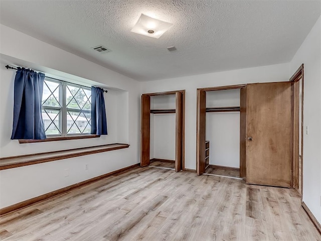 4325 NW 44th St, Oklahoma City, OK 73112 - unfurnished bedroom with a textured ceiling, light wood finished floors, and multiple closets