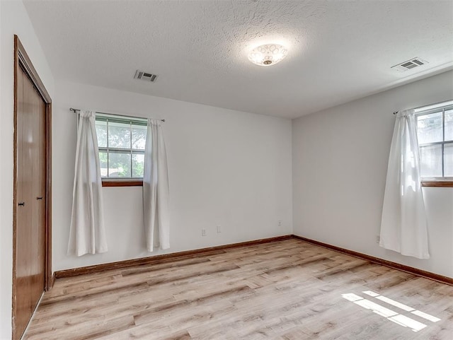 4325 NW 44th St, Oklahoma City, OK 73112 - unfurnished bedroom featuring multiple windows, light wood-style flooring, a textured ceiling, and a closet