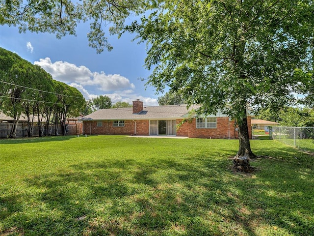 4325 NW 44th St, Oklahoma City, OK 73112 - rear view of house with a fenced backyard, brick siding, and a chimney