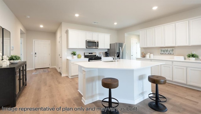 10201 NW 28th Ter, Yukon, OK 73099 - kitchen with stainless steel appliances, light wood-style floors, a center island with sink, a kitchen bar, and white cabinetry