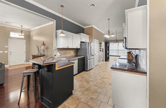 1204 NW 190th Pl, Edmond, OK 73012 - kitchen with stainless steel appliances, white cabinets, a peninsula, decorative backsplash, and a breakfast bar