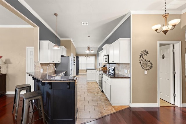 1204 NW 190th Pl, Edmond, OK 73012 - kitchen with appliances with stainless steel finishes, a kitchen breakfast bar, decorative backsplash, white cabinetry, and ornamental molding