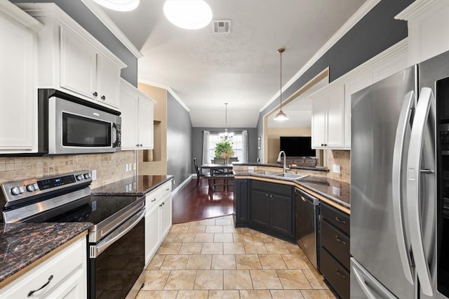1204 NW 190th Pl, Edmond, OK 73012 - kitchen with appliances with stainless steel finishes, crown molding, white cabinets, decorative backsplash, and hanging light fixtures