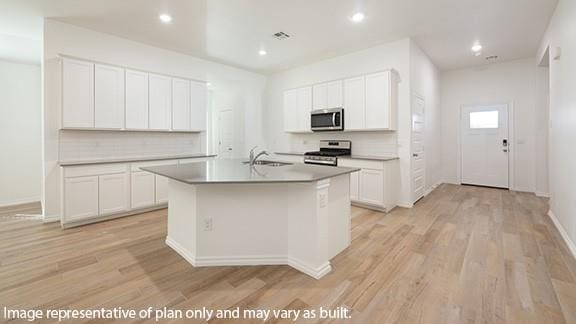 10200 NW 28th Ter, Yukon, OK 73099 - kitchen featuring stainless steel appliances, tasteful backsplash, light wood finished floors, a center island with sink, and recessed lighting