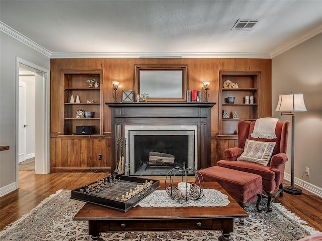 1718 Guilford Ln, Oklahoma City, OK 73120 - living area featuring a fireplace with flush hearth, ornamental molding, built in shelves, wood finished floors, and wooden walls