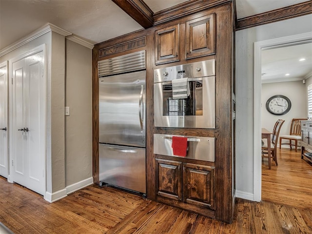 1718 Guilford Ln, Oklahoma City, OK 73120 - kitchen with appliances with stainless steel finishes, a warming drawer, ornamental molding, and dark wood-type flooring