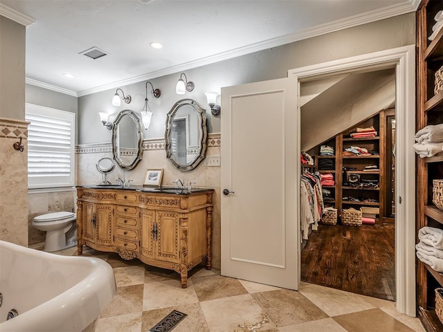 1718 Guilford Ln, Oklahoma City, OK 73120 - bathroom featuring ornamental molding, tile walls, double vanity, a bathtub, and a spacious closet