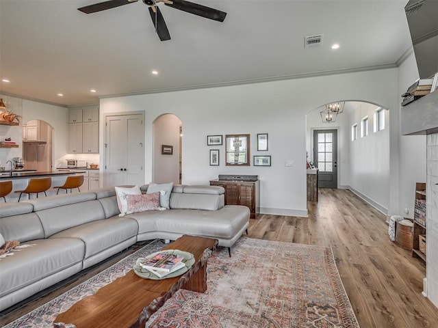 7290 NE Hawk Dr, Piedmont, OK 73078 - living room with arched walkways, ornamental molding, light wood-type flooring, a ceiling fan, and recessed lighting