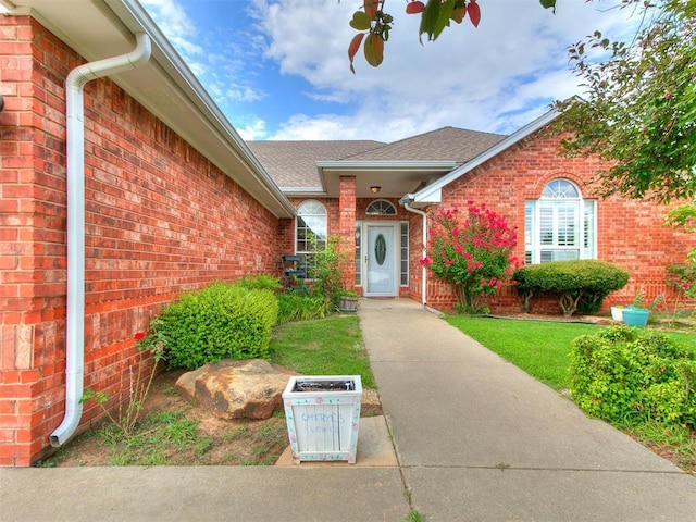 4821 SE 52nd St, Oklahoma City, OK 73135 - view of exterior entry with brick siding, a shingled roof, and a yard