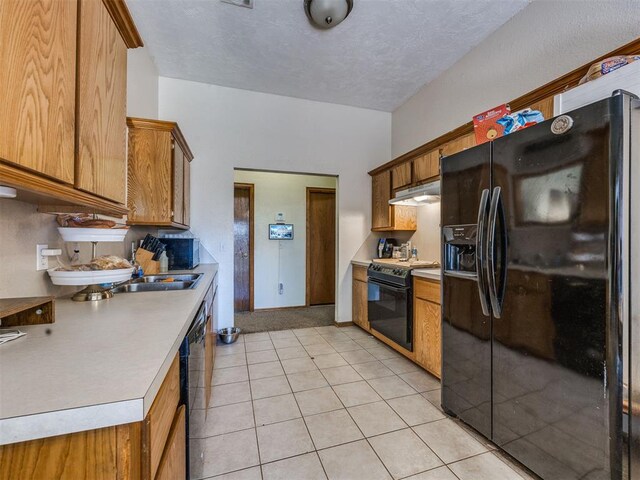12320 NW 4th St, Yukon, OK 73099 - kitchen with black appliances, light countertops, under cabinet range hood, brown cabinetry, and a textured ceiling