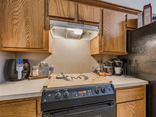 12320 NW 4th St, Yukon, OK 73099 - kitchen featuring black range with electric cooktop, under cabinet range hood, light countertops, and brown cabinetry