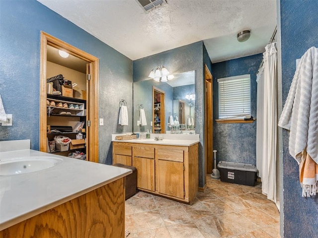 12320 NW 4th St, Yukon, OK 73099 - bathroom with vanity, a textured wall, a textured ceiling, and a spacious closet