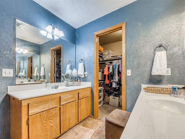 12320 NW 4th St, Yukon, OK 73099 - bathroom with two vanities, a walk in closet, and a textured wall