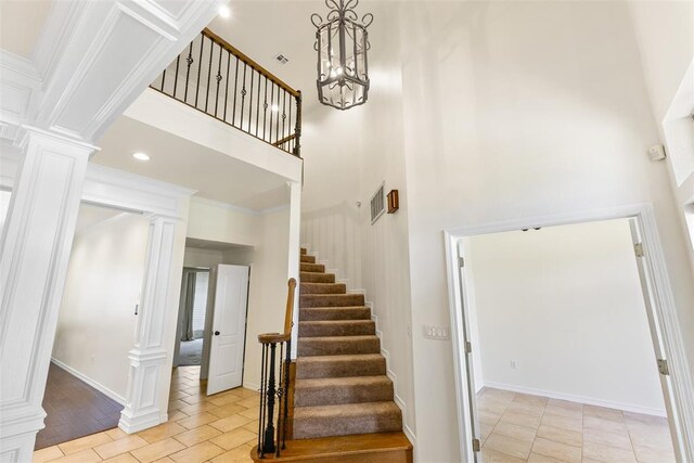 1505 S Augusta Dr, Ada, OK 74820 - stairway featuring decorative columns, a high ceiling, tile patterned flooring, and a chandelier