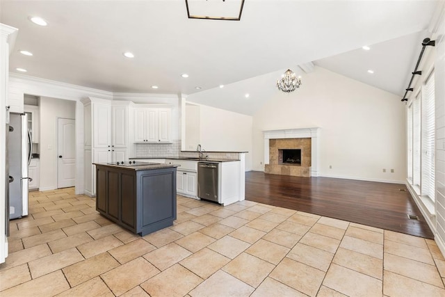 1505 S Augusta Dr, Ada, OK 74820 - kitchen featuring appliances with stainless steel finishes, white cabinetry, open floor plan, a center island, and tasteful backsplash
