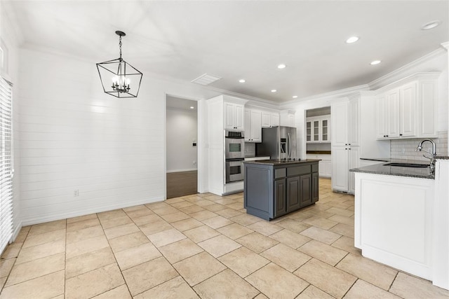 1505 S Augusta Dr, Ada, OK 74820 - kitchen featuring white cabinetry, appliances with stainless steel finishes, a center island, backsplash, and a chandelier