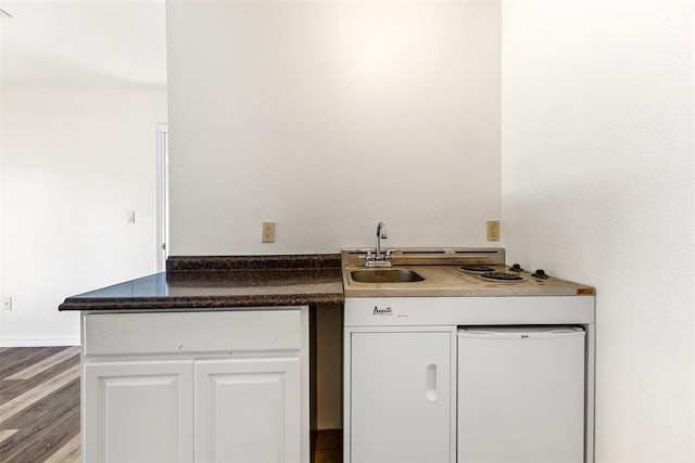 1505 S Augusta Dr, Ada, OK 74820 - kitchen with white cabinets, wood finished floors, and dark countertops